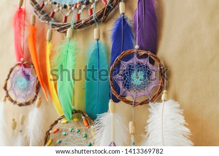 Handmade colorful dreamcatcher details with painted rainbow feathers on striped craft wrapping paper background