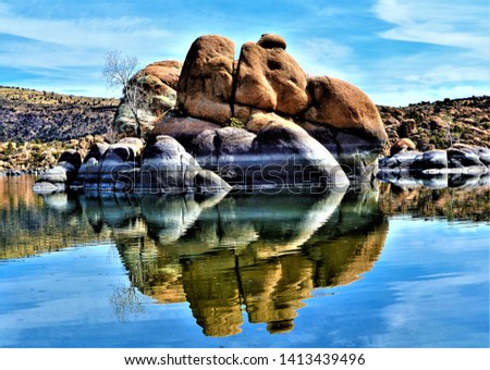 Watson Lake in Prescott Arizona's water surface is about 380 surface acres and distinguished by its sky blue calm waters surrounded by huge granite boulders with protruding vegetation. Royalty-Free Stock Photo #1413439496