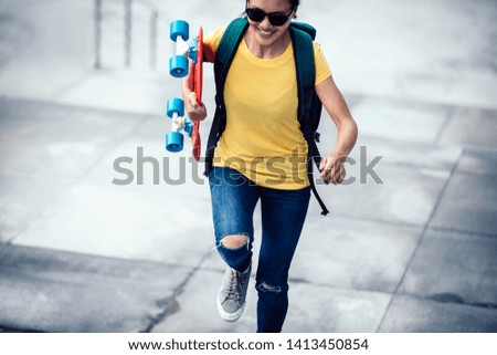 Woman skateboarder walking with skateboard in hand at city stairs
