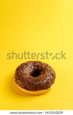 chocolate donut on yellow background top view
