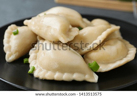 Tasty dumplings served with green onion on plate, closeup