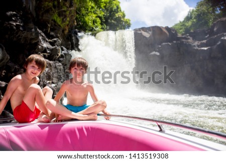 Children, enjoying the waterfall, near the island of Mauritius from a boat trip. Family vacation. Quality family time