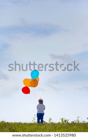 Little boy, toddler, child playing with colorful balloons in the park on kids day, sunny summer afternoon in nature