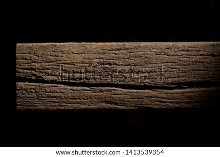 Old rotten logs stacked in crossbeams on a black background
