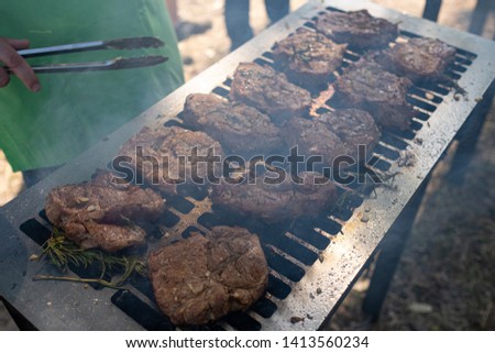 Grilling pork meat with barbecue stuff. Horizontal close up shot with a selective focus