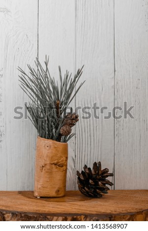 Pine branch and cone on a wooden stand