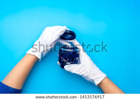 Top view female hand wearing white gloves holding camera lens. Professional photo camera repair.