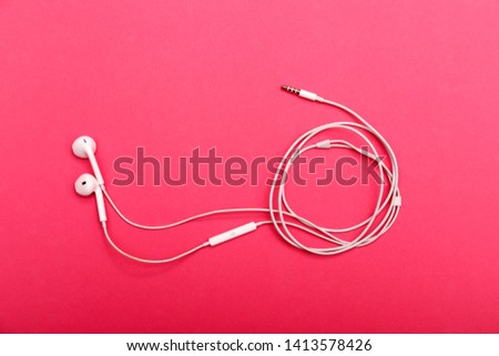 Headphones on a pink background. White earphones on a purple background. View from above. Copy space for text. Minimal style. 