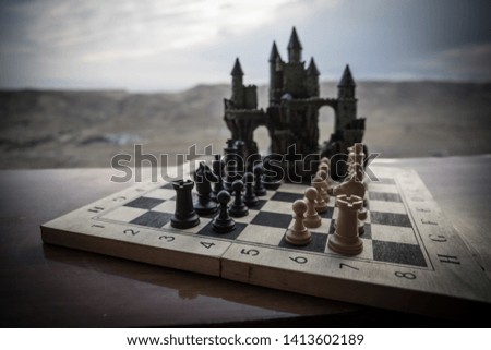 Chess board game concept of business ideas and competition. Chess figures and old medieval castle on a chessboard. Outdoor sunset background. Selective focus
