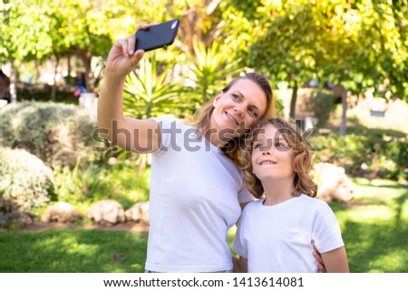 Happy mother and son in a park making a selfie