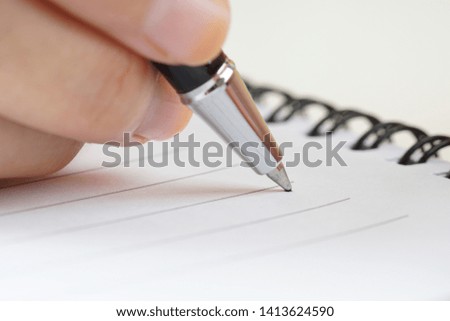 Woman hand holding a silver pen with a note book