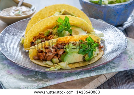 Smoky Mexican pork and bean tacos with lettuce and avocado salad