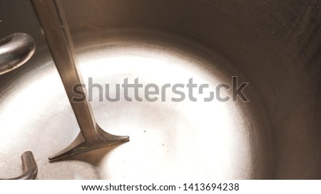 Close-up of milk pouring out in the large mixer for the dough on the kitchen in bakery. Stock footage. Preparation of dough