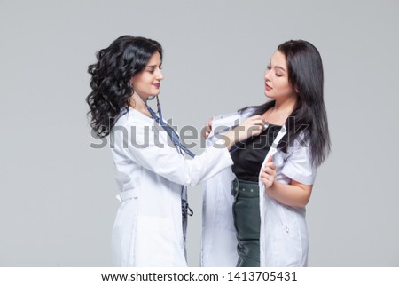 Female doctor examining another woman with stethoscope