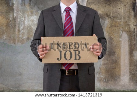 business man holding cardboard with the text I NEED A JOB
