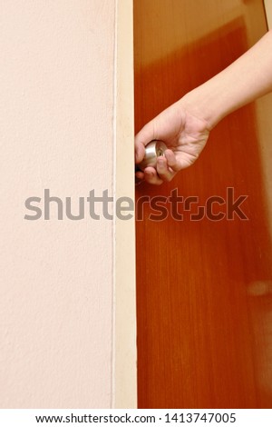hand twisting silver knob to opened wooden door in home