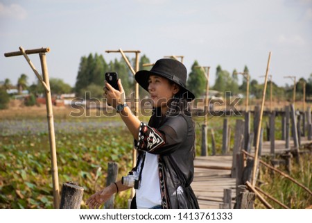 Travelers thai women people travel visit and posing portrait for take photo on Kae Dam long wood bridge in Maha Sarakham Province, northeastern Thailand.