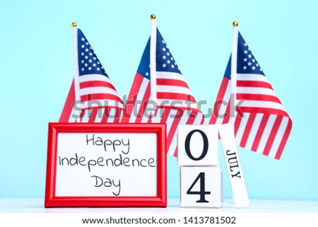 Text Happy Independence Day with american flags and cube calendar on blue background