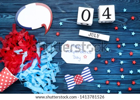 Text Happy Independence Day with paper stars, speech bubble and cube calendar on wooden table