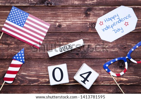 Text Happy Independence Day with american flag and cube calendar on brown wooden table