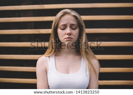 Concept of cheerless and joyless, disappointed hipster girl feeling sad and melancholy while standing on publicity area, regrettable offended Caucasian woman 20s with emotional pain on face