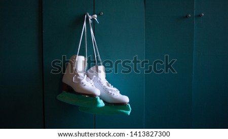 Women's figure skates hang on the locker door in the locker room.