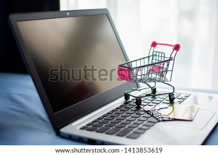 shopping cart and credit card on computer, shopping online concept. subject is blurred and low key.