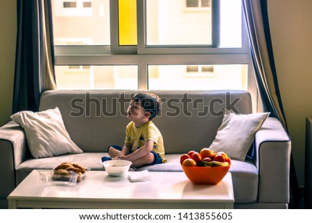 Toddler having breakfast at home while whatching cartoons. Child eat porridge and croissant. Healthy nutrition. Healthy food. Healthy homemade eating for kids.