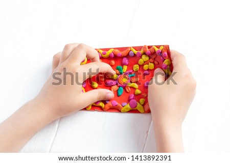 A child kneads plasticine and sculpts a juicy, bright multi-colored rug. Tutoring with children.