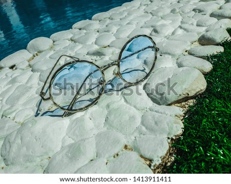 Blue glasses on white stones by the pool