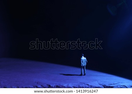 A picture of a miniature man stands in the spotlight looking forward .Concept of facing the unknown, taking a decision and finding solution.