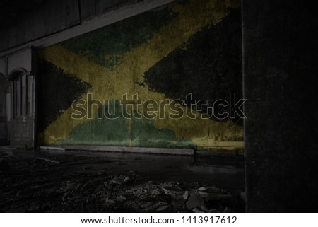 painted flag of jamaica on the dirty old wall in an abandoned ruined house. concept