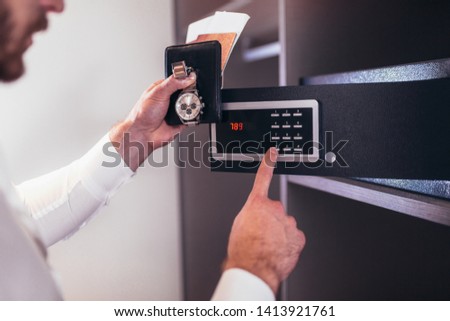 Men's hand opens a safe hidden in the wardrobe. Small home or hotel safe  Royalty-Free Stock Photo #1413921761