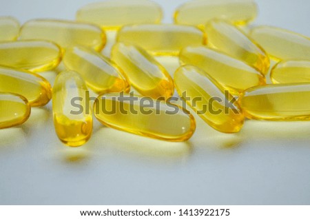 Yellow capsules lie on a white background. Omega capsules