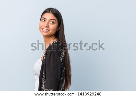 Young natural and pretty arab woman looks aside smiling, cheerful and pleasant.