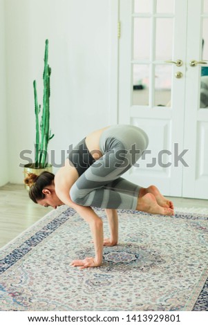 Young attractive smiling woman practicing yoga in a bright room