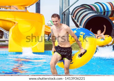 excited man having fun on water slide in tropical aqua park