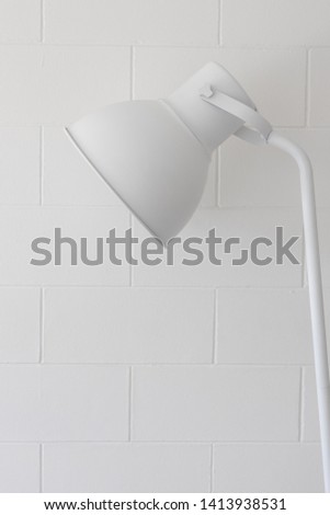 Closeup of adjustable single simple modern white lamp on block brick wall texture background.