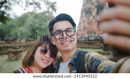 Traveler Asian couple using smartphone taking selfie while spending holiday trip at Ayutthaya, Thailand, Couple enjoy their journey at amazing landmark in traditional city. 