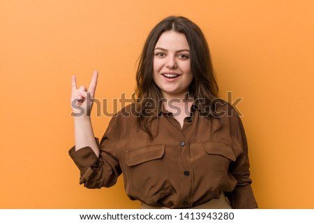 Young curvy russian woman showing a horns gesture as a revolution concept.