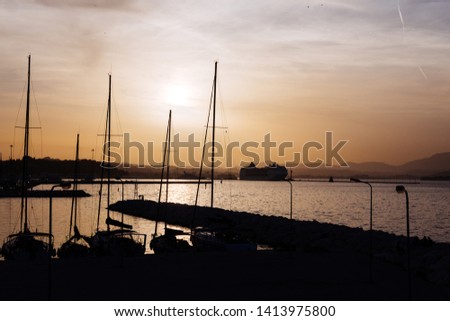 Silhouette of a fisherman boat on the seafront in bright colorful orange sun color at sunset.