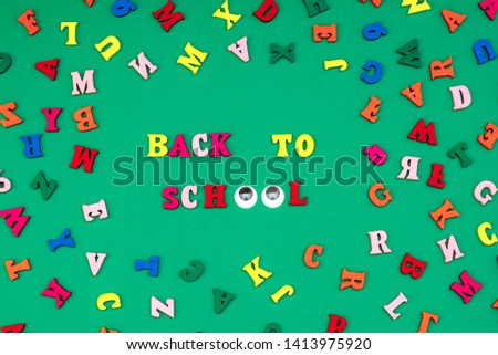 Colored letters of the alphabet from a tree on a green background. Back to school.