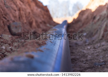 Plastic water pipe is in the trench in the direction under a blue sky residential buildings Close up Royalty-Free Stock Photo #1413982226