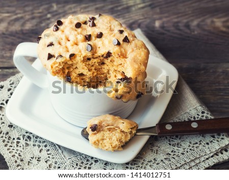 Fresh homemade cake in mug with peanut butter and chocolate chips on rustic wooden background. Cooked in microwave.  Royalty-Free Stock Photo #1414012751