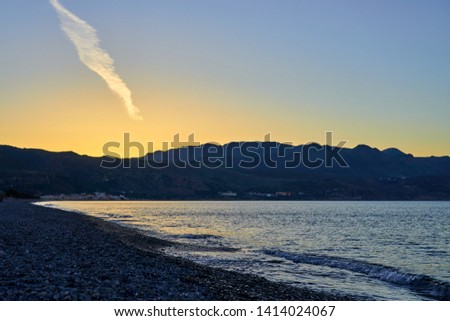                           The Sunset on the pebble beach with hills on the background, Kolymbari, Crete, Greece. 