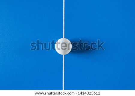 A white tennis ball for a table tennis at the blue background.