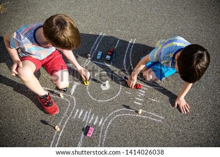 Two brothers sibling kid boy having fun with picture drawing traffic car with chalks. Creative leisure for children outdoors in summer. Difficult traffic rules education friendship concept.