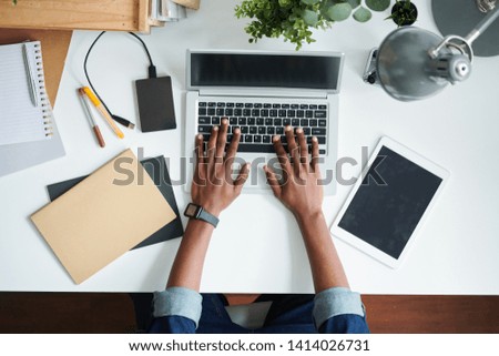 Overview of human hands over desk and laptop keypad during work over new business or educational project or report