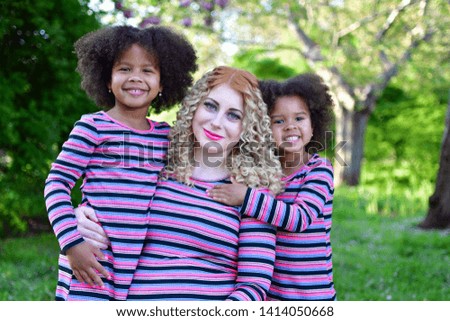 African American sisters are playing in the park. pregnant girl smiling in a blooming spring park, the girl is walking in a  syringa vulgaris flowers parkbushes of lilac