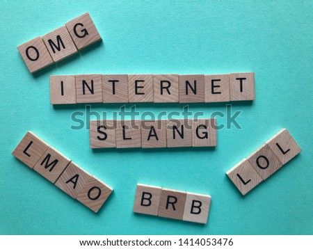 Internet slang. Acronyms : BRB (Be Right Back), LOL, OMG, and LMAO used as abbreviations in text messages, in wooden letters on a turquoise background with copy space.